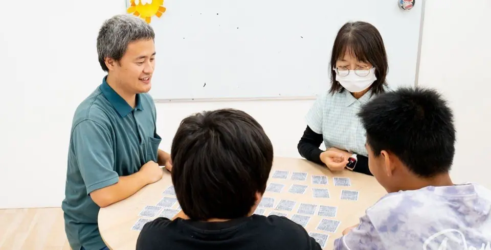 スタッフと子どもたちが少人数でカードゲームをする様子