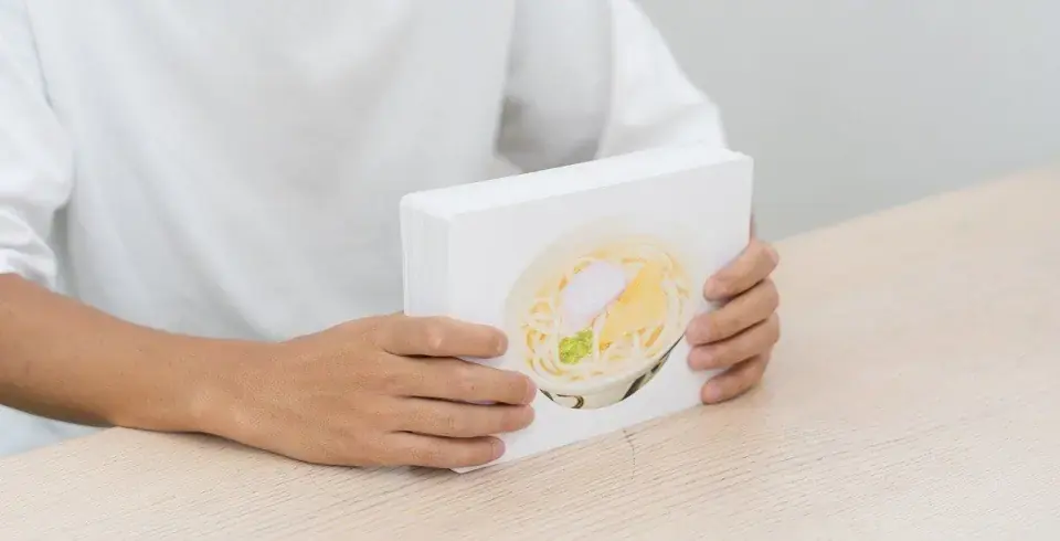 うどんの写真カードを持つスタッフの手元