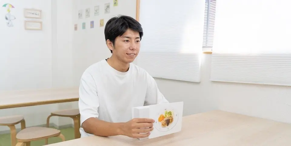 絵カードを見せながら話しかけるスタッフ