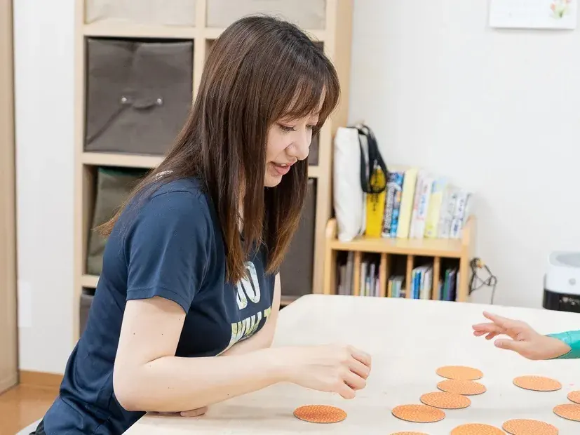 スタッフがテーブルの上の教材を使って、お子さまと一緒に取り組む様子