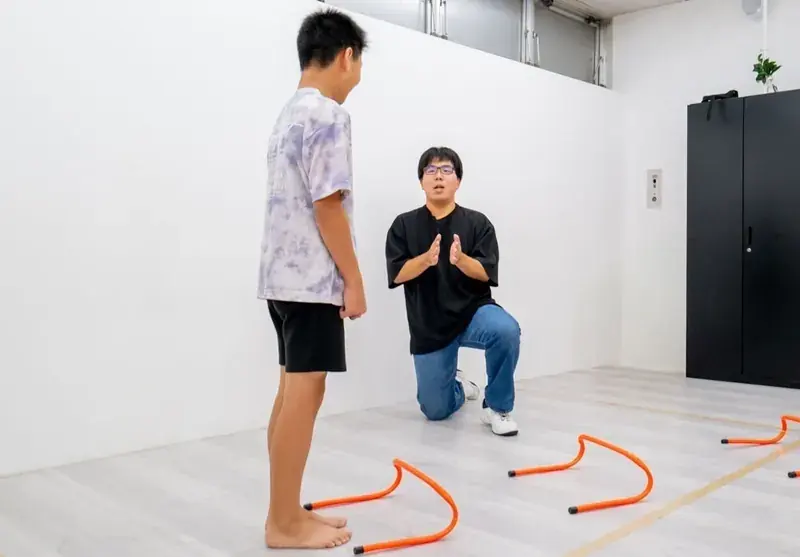 ミニハードルの前でスタッフの説明を聞く子ども